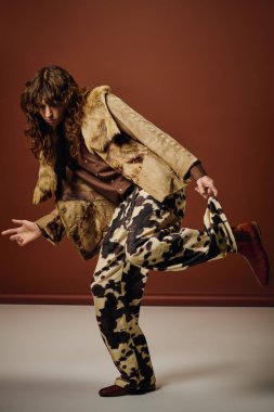 Kendine güveni tam bir genç adam, şatafatlı bir şekilde poz veriyor, canlı bir arka plana karşı..