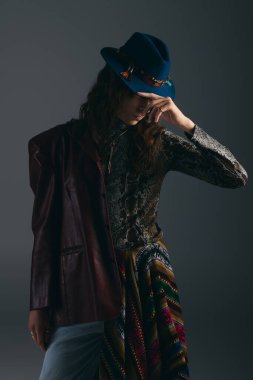 Genç, yakışıklı bir adam düşünceli bir şekilde stüdyoda poz veriyor, dokuların ve kalıpların karışımını sergiliyor..