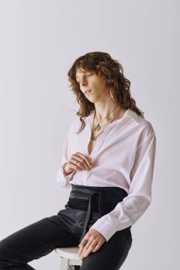 Kıtır gömlekli yakışıklı genç bir adam şık bir stüdyoda tarzını ve karizmasını sergiliyor..