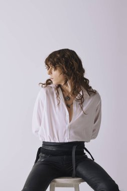 Yakışıklı genç adam bir taburede oturuyor, kendine has tarzını zarafet ve duruşuyla sergiliyor..