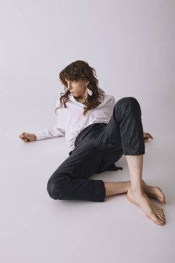 Şık bir genç adam minimalist bir ortamda rahatlıyor, modaya uygun kıyafetiyle hava atıyor..