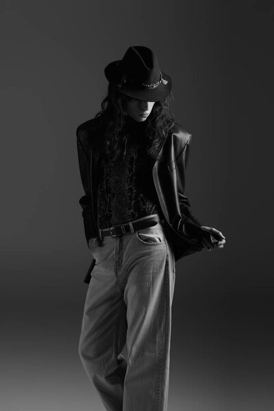 Красивый молодой человек в элегантной одежде уверенно позирует в минималистском пространстве..