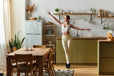 Güzel, genç bir kadın, modern bir mutfakta dans ederek mutluluğunu ifade eder..