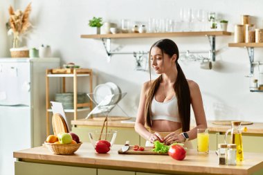 Formda genç bir kadın modern mutfağında canlı malzemeler içeren sağlıklı bir salata hazırlıyor..