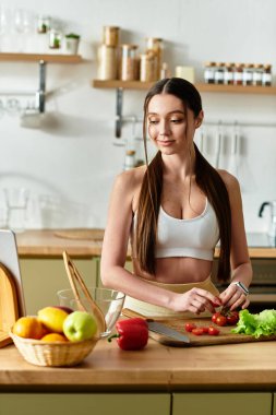 Spor kıyafetli fit bir kadın şık mutfağında canlı bir salata yapmak için sebze doğruyor..