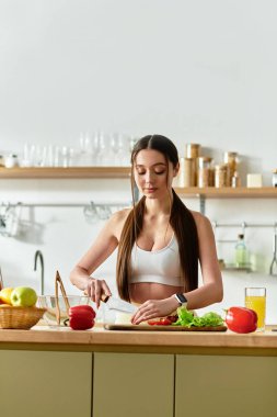 Zinde bir kadın, modern mutfağında lezzetli bir salata yapabilmek için taze sebzeleri ustalıkla dilimliyor..