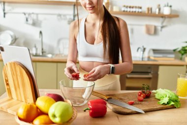 Spor kıyafetli genç bayan taze sebzelerle dolu renkli bir salata yapıyor..