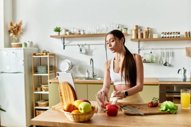 Formda genç bir kadın şık mutfağında sağlıklı bir salata için taze sebzeler doğruyor..