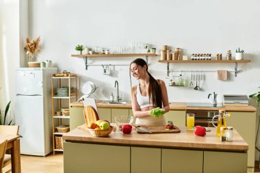 Spor giyim sektöründe genç bir kadın modern mutfağında taze bir salata hazırlamaktan zevk alıyor..