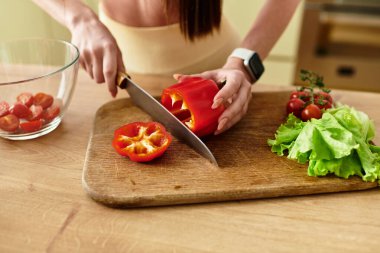 Genç bir kadının kırpılmış görüntüsü sağlıklı bir salata hazırlıyor, modern bir mutfakta renkli sebzeler doğruyor..