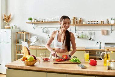 Formda bir kadın şık mutfağında canlı bir salata ve taze sebzeler pişirir..