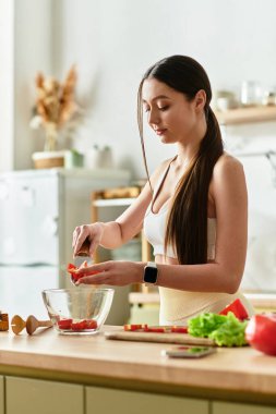 Spor giyim sektöründe genç bir kadın ustalıkla sebzeleri doğruyor ve mutfağında sağlıklı bir salata yapıyor..