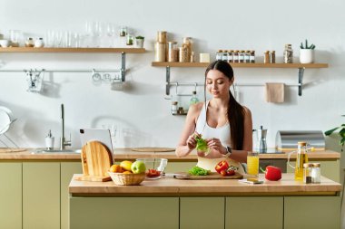Spor kıyafetleri içinde güzel bir kadın mutfağında canlı bir salata hazırlıyor..