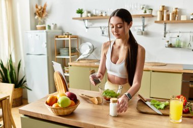 Spor sütyenli genç bir kadın şık mutfağında taze ve sağlıklı bir salata yapar..