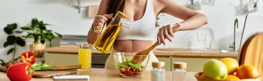 Spor sütyenli, formda genç bir kadın parlak mutfağında taze salata yapıyor.