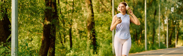 A beautiful athletic woman jogs energetically along a scenic path, surrounded by vibrant trees.