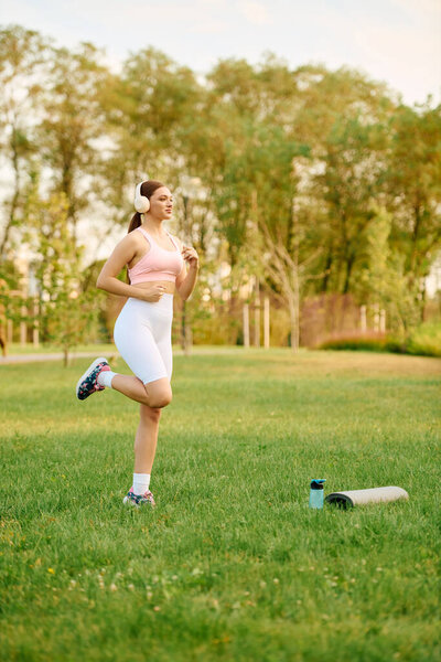 A vibrant young woman jogs gracefully in a sunny park, enjoying fitness and nature.