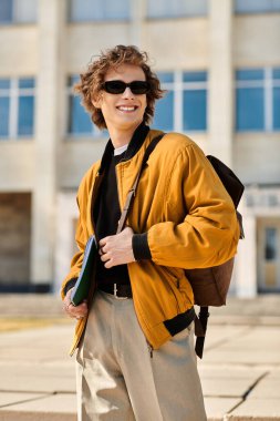 A confident young man with a stylish haircut smiles casually in front of a university. clipart