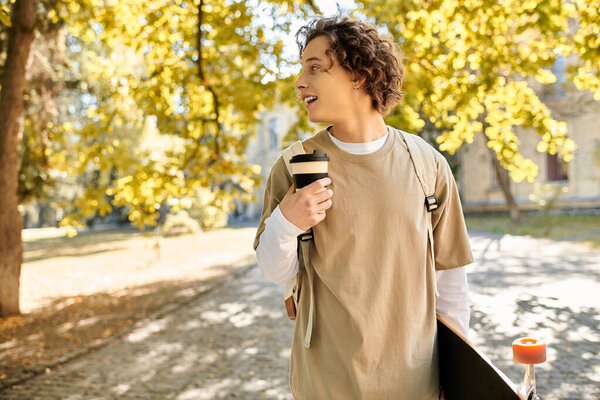 A fashionable young man strolls through a sunny park, coffee in hand and skateboard nearby.