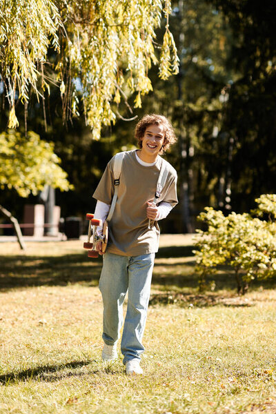 Стильный молодой человек прогуливается по парку со скейтбордом, наслаждаясь теплым солнцем.