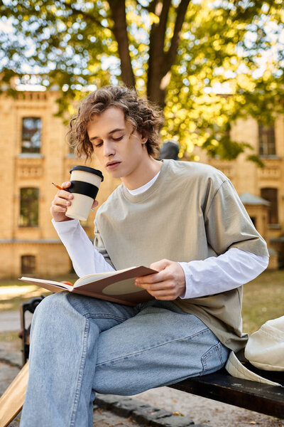 Студент в повседневной одежде наслаждается книгой и кофе под большим деревом в кампусе.