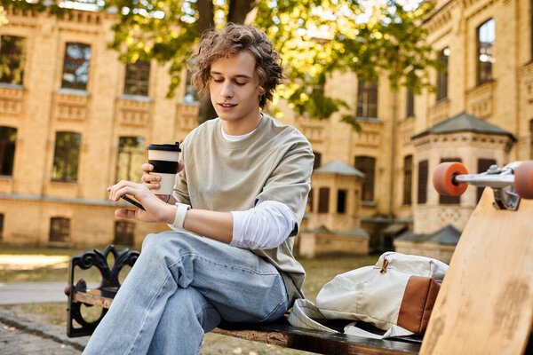 Young stylish man relaxes on a bench, sipping coffee and glancing at his watch in a sunny park.