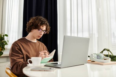 Kıvırcık saçlı genç adam rahat ve şık yaşam alanına notlar yazıyor..