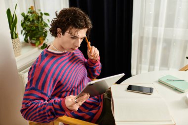 İkili olmayan, kıvırcık saçlı genç bir insan şık, renkli dairesinde dikkatle çalışıyor..