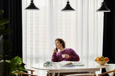 Parlak giyimli bireysel çayını yudumlarken evde bir telefon görüşmesi yapıyor..