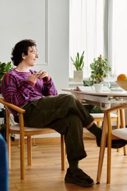 Kıvırcık saçlı birey şık bir ev ortamında canlı bir kazakla rahatlar..