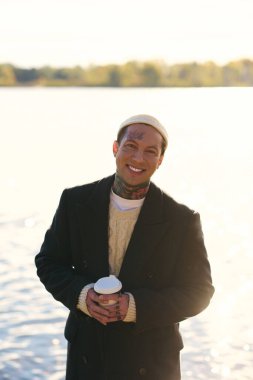 Dövmeli genç adam, sakin rıhtımda rahatlarken kendine güveniyor..