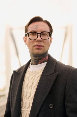 Yakışıklı bir adam modaya uygun bir kıyafet giyerken ve dövmelerini gösterirken kendine güvenir..