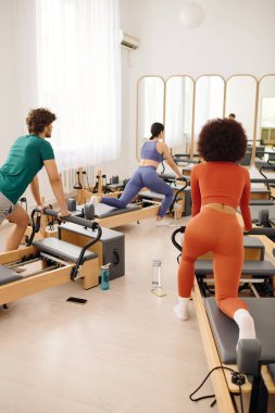 Coşkulu bireyler fitness üzerine odaklanmış parlak, ferah bir pilates stüdyosuna girerler..