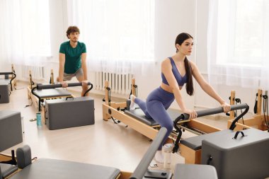 Katılımcılar ferah, iyi aydınlatılmış bir stüdyoda canlandırıcı bir pilates çalışmasına katılıyorlar..