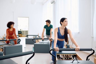 Pilates sınıfına aktif olarak katılan bireyler grubu, güç ve odaklanma gösteriyor.