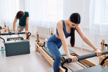 A woman concentrates on pilates with a male partner in a bright studio. clipart