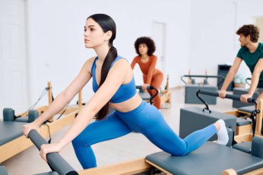 Katılımcılar zorlu bir pilates antrenmanına girişerek güç ve esnekliği artırıyorlar..