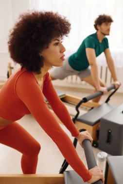 İki birey, parlak bir stüdyo ortamında canlı bir pilates egzersizi sırasında yoğun bir şekilde odaklanır..