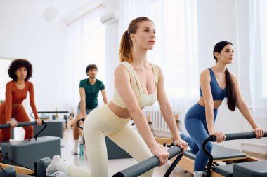 Geniş ve iyi aydınlatılmış bir stüdyo ortamında pilates egzersizlerine odaklanan dinamik bir grup..
