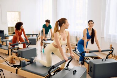 Arkadaşlarla güneşli bir stüdyoda pilates yenilikçileri kullanarak grup çalışması yapılır..