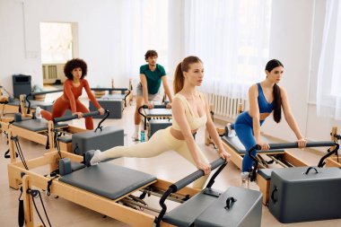 Güneşli bir odada dört kişi, reformcular üzerinde pilates yapıyor..