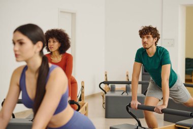 Katılımcılar modern bir pilates stüdyosunda aktif olarak antrenman yaparak güç ve dengeyi arttırıyorlar..
