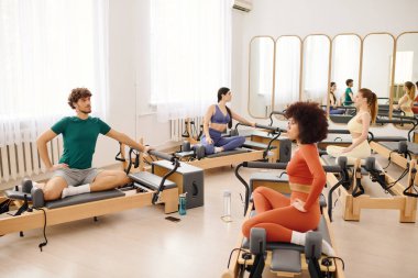 Katılımcılar, büyük bir stüdyoda güç ve esneklik odaklı dinamik bir pilates dersinin keyfini çıkarıyorlar..