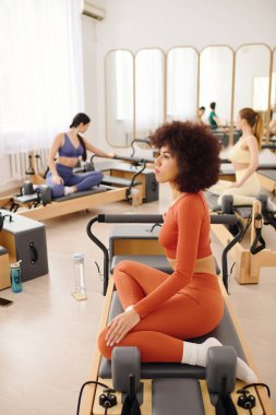 Katılımcılar modern bir stüdyoda pilates rutinleri yoluyla güç ve esnekliği artırıyorlar..