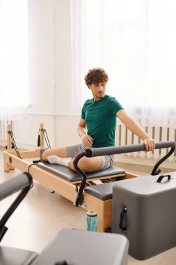 Bir insan özel ekipman kullanarak pilates yapar, hareketlerine ve formuna konsantre olur..