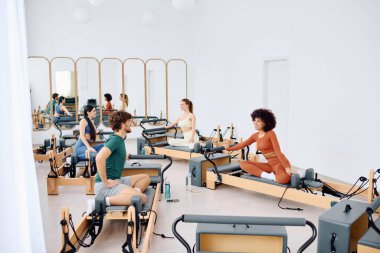 Odaklanmış insanlar güç ve esnekliği arttırmak için parlak bir stüdyoda pilates çalışırlar..
