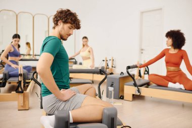 Katılımcılar dikkatle pilates rutinlerine odaklanarak esnekliği ve çekirdek gücünü artırıyorlar.