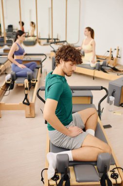 Modern bir pilates stüdyosunda, insanlar reformcuları kullanırken kendi formlarına odaklanırlar..