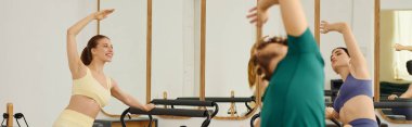 Coşkulu bireyler, parlak bir pilates stüdyosunda esneme ve güçlendirme egzersizleri yapıyorlar..