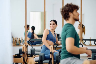 İki birey güneşli ve davetkar bir stüdyoda dinamik ve odaklanmış bir pilates egzersizinin tadını çıkarıyor..